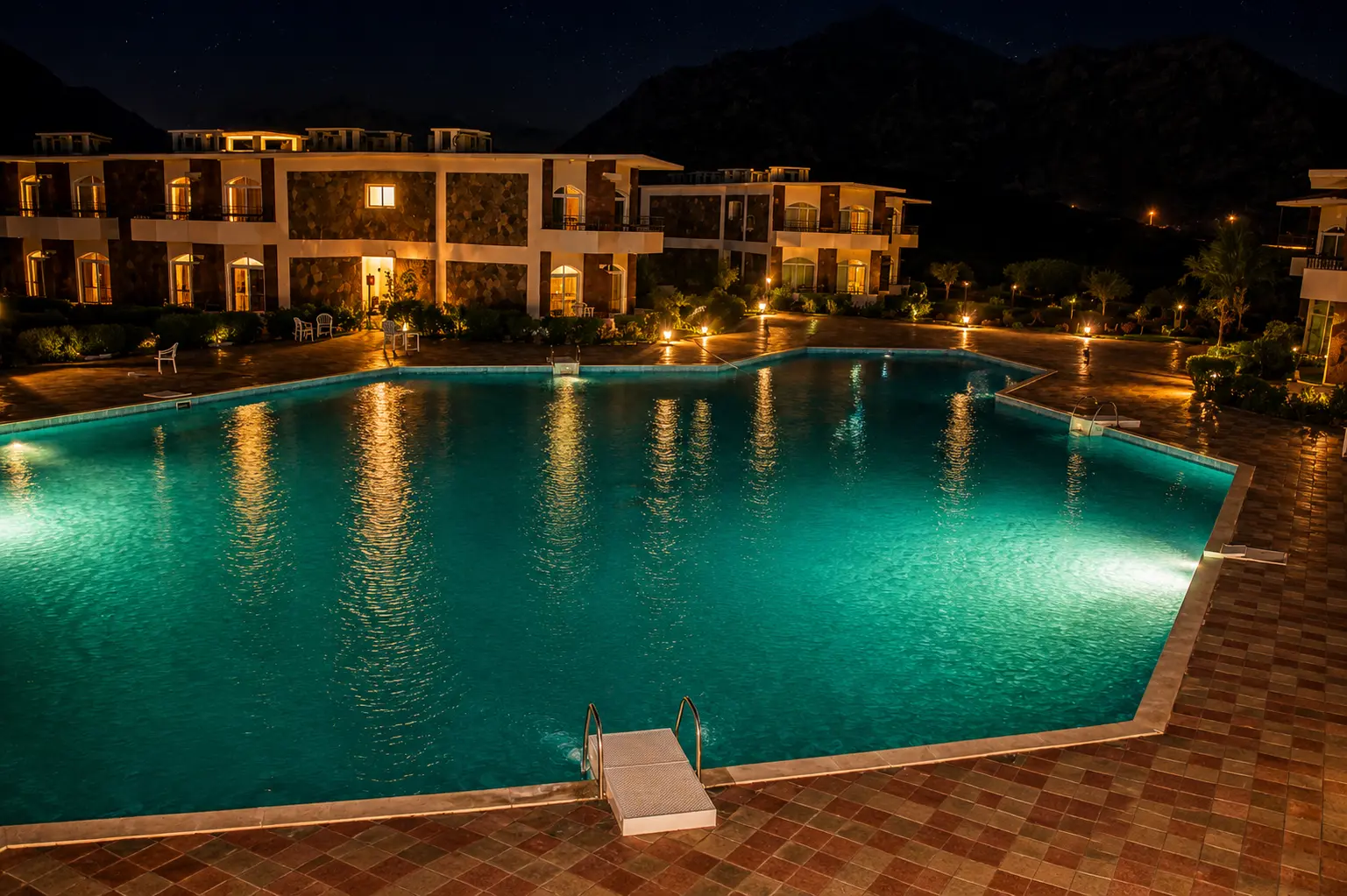 The large pool lit at night with the village reflected in the water